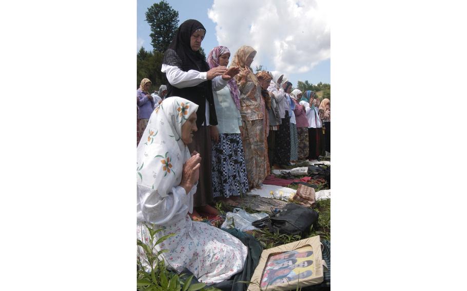 Sida Mehanovic, too weak to stand, prays over a picture of her missing family members at the eighth Srebrenica memorial ceremony at the nearby town of Potocari on Friday. Most of the 7,500 to 10,000 men killed after the fall of Srebrenica on July 11, 1995, were Muslim. A memorial is being built at the sight.