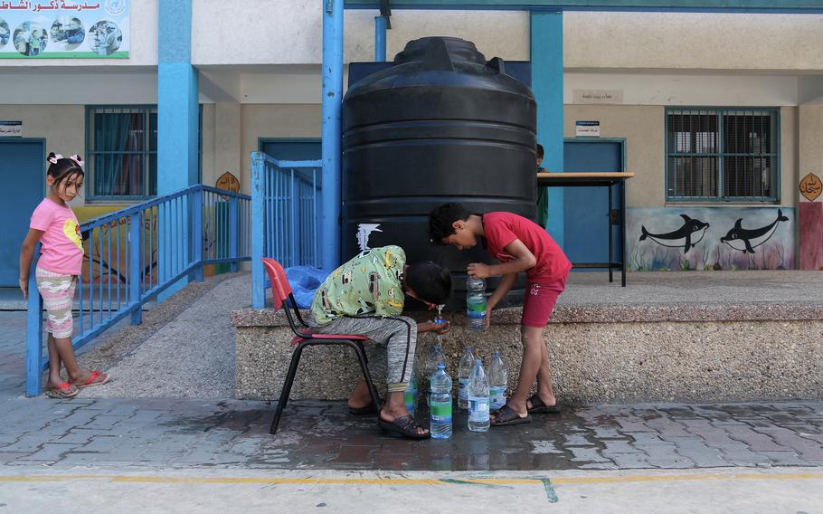 Ahmed Hassanian, left, and his brother Moataz are filling water bottles. 