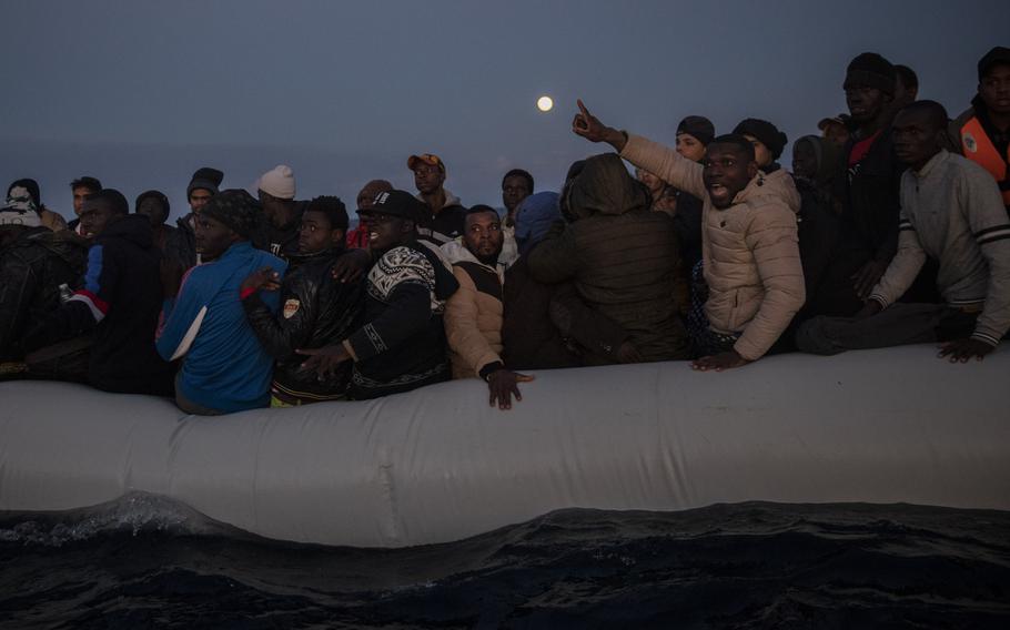 Migrants and refugees from different African nationalities react on an overcrowded wooden boat, as aid workers of the Spanish NGO Open Arms approach them in the Mediterranean Sea, international waters, off the Libyan coast, in this Friday, Jan. 10, 2020, file photo. Libyan security forces raided and violently broke up a protest sit-in by migrants outside a shuttered U.N. community center in the capital of Tripoli, activists and migrants said Monday.