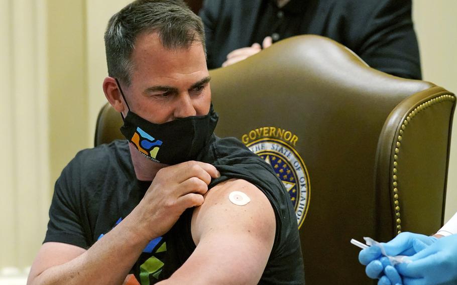 Oklahoman Gov. Kevin Stitt looks back at the needle after looking away while being administered the Johnson & Johnson vaccine on March 29, 2021, in Oklahoma City. Oklahoma’s Republican governor and the state attorney general are suing in federal court to exempt the state’s National Guard from a Biden administration COVID-19 vaccine mandate. 