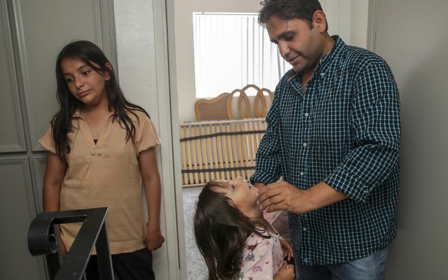 Sayed Omer Sadat, 35, an Afghan refugee, with his two daughters Asma, 11, left, and Aqsa, 6, is seen in his new apartment in El Cajon, Calif., on Monday, Aug. 23, 2021.