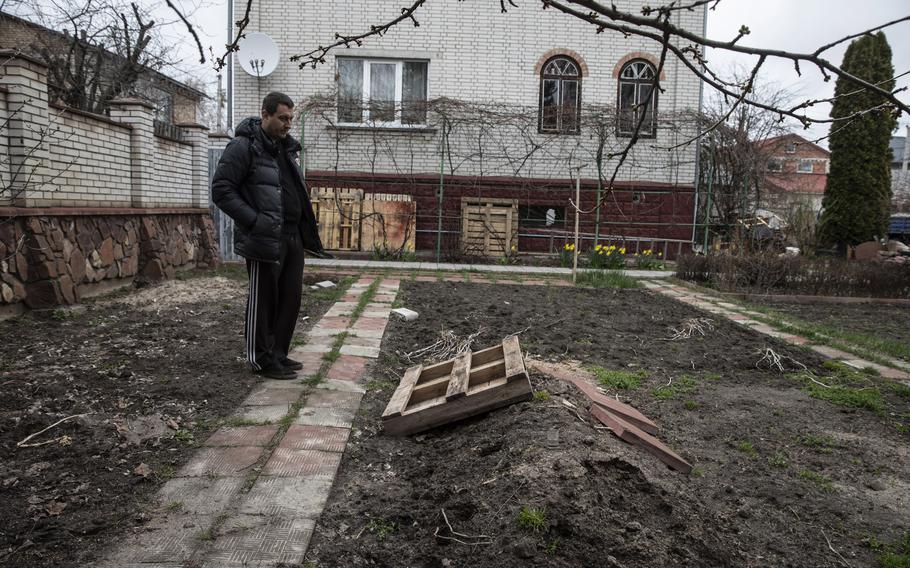 Pavlo Prykhodko stands by his father’s grave in the backyard of his parent’s home in Vorzel, Ukraine, on April 13, 2022.