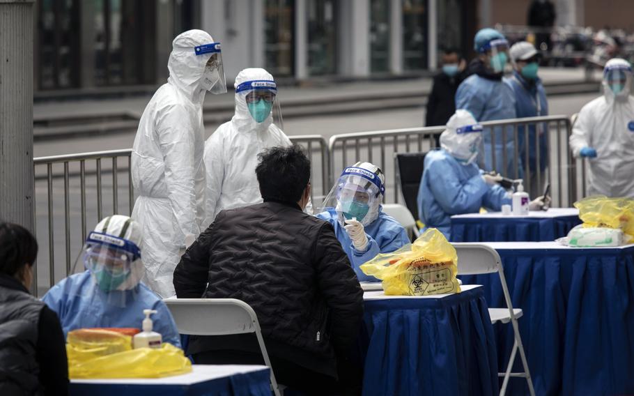 Health workers tests for COVID outside of a clothing market in Shanghai on March 10 2022. 
