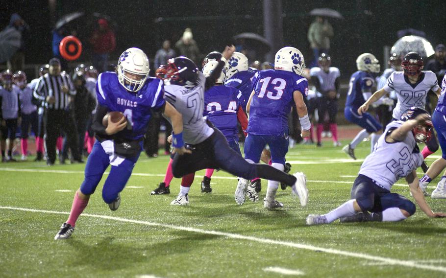 Ramstein quarterback Lucas Hollenbeck rolls to the right while Lakenheath’s Lucius Bowman dives at him during Friday evening’s game at Ramstein, Germany.
