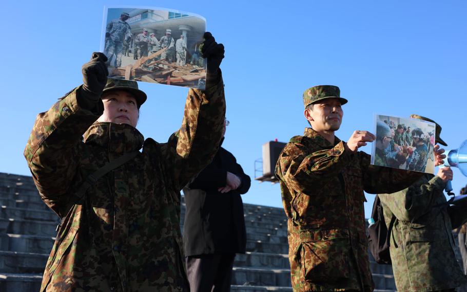 Japanese soldiers show pictures of recovery efforts for the 2011 earthquake and tsunami to U.S. soldiers visiting Nobiru Beach in Miyagi prefecture, Japan, on Dec. 13.