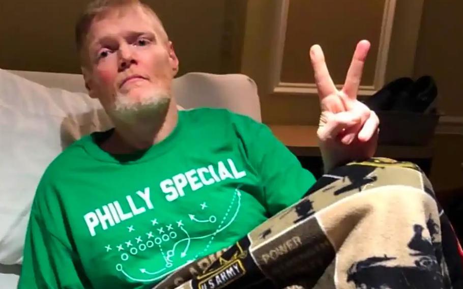 Kevin McCrea flashes a peace sign while wearing a T-shirt that reads “Philly Special” with his legs covered by a U.S. Army blanket.
