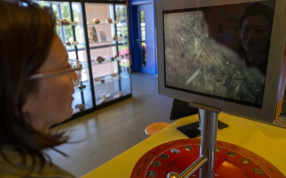 A visitor to the volcano museum in Mendig, Germany, on Sept. 21, 2024, examines the magnified crystalline structure formed in volcanic rock. This exhibit highlights the intricate formations created during the cooling of molten lava.
