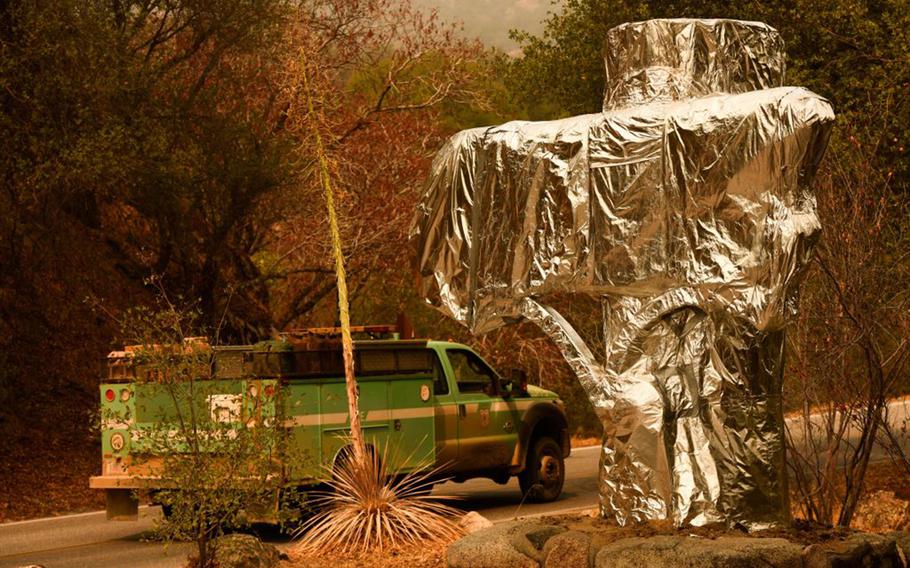 A U.S. Forest Service vehicle drives past the Sequoia National Park historic park entrance sign wrapped in fire resistant foil along Generals Highway during a media tour of the KNP Complex fire in the Sequoia National Park near Three Rivers, Calif., on Sept. 18, 2021.