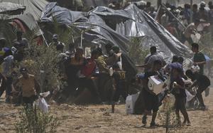 Palestinians rush to collect aid near tent encampments.