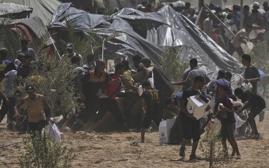 Palestinians rush to collect aid near tent encampments.