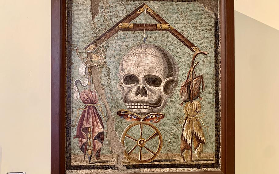 a mosaic featuring a skull in the middle, hanging on a wall