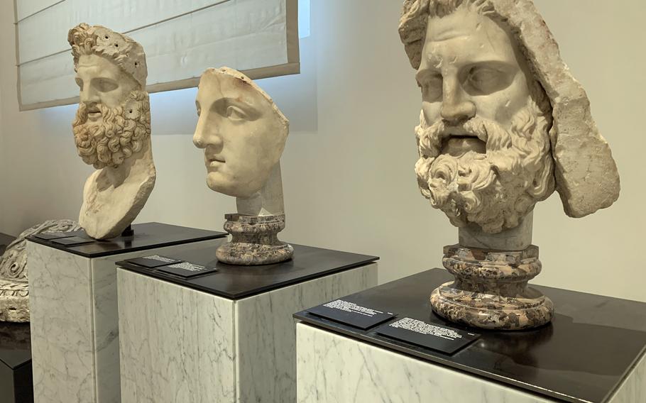 three marble face sculptures on stands
