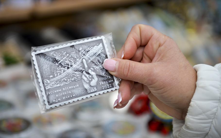 Tetiana Zhornova, a street vendor in Kyiv, Ukraine, holds a souvenir on Oct. 27, 2022, commemorating the sinking of the Russian warship Moskva. The street vendors on Volodymyrska Street said they stopped selling Russian memorabilia after that country’s invasion of Ukraine this year. 