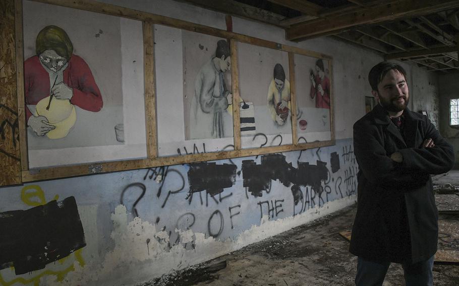 Landon Grove, director and curator of the Fort Ritchie Museum, stands near an original mural. The art work was uncovered in a building at Fort Ritchie where Nisei,  second-generation Japanese-Americans, worked during WWII. The now decommissioned US Army post was used from 1942-1946 as an Army Military Intelligence Training Center. In 1944, over 500 Nisei worked in counterintelligence at the base.