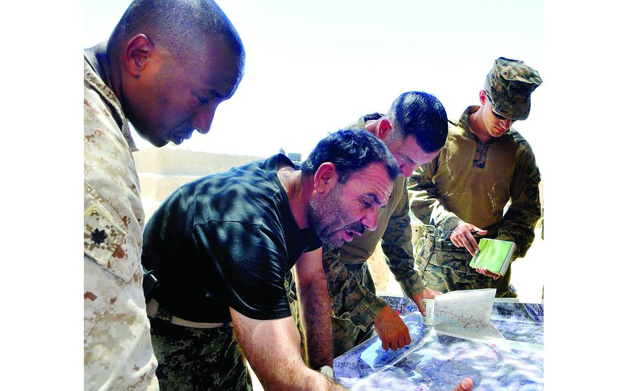NATO coalition troops and an Afghan army officer, including, from left, security force advisory team leader Lt. Col. Jonathan Loney, 2nd Brigade, 215 Corps commander Brig. Gen. Abdul Wasea, and police advisory team leader Maj. Brian T. Mulvihill, examine a map of Sangin district, which has become a focus for both the Taliban and the Afghan government in recent weeks. 