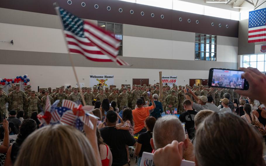 American flags fly as soldiers greet their loved ones.