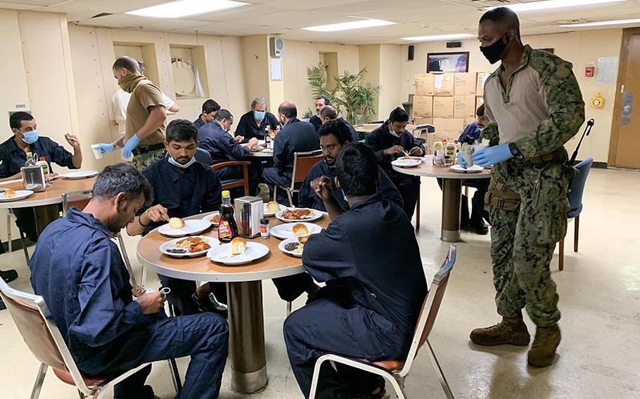 Petty Officer 1st Class Magezi Johnson and Petty Officer 3rd Class Gurney White, aboard the Military Sealift Command fleet replenishment oiler USNS Patuxent, serve hot meals to rescued crew members from the commercial ship Falcon Line, while underway in the Gulf of Aden, June 8, 2021. 