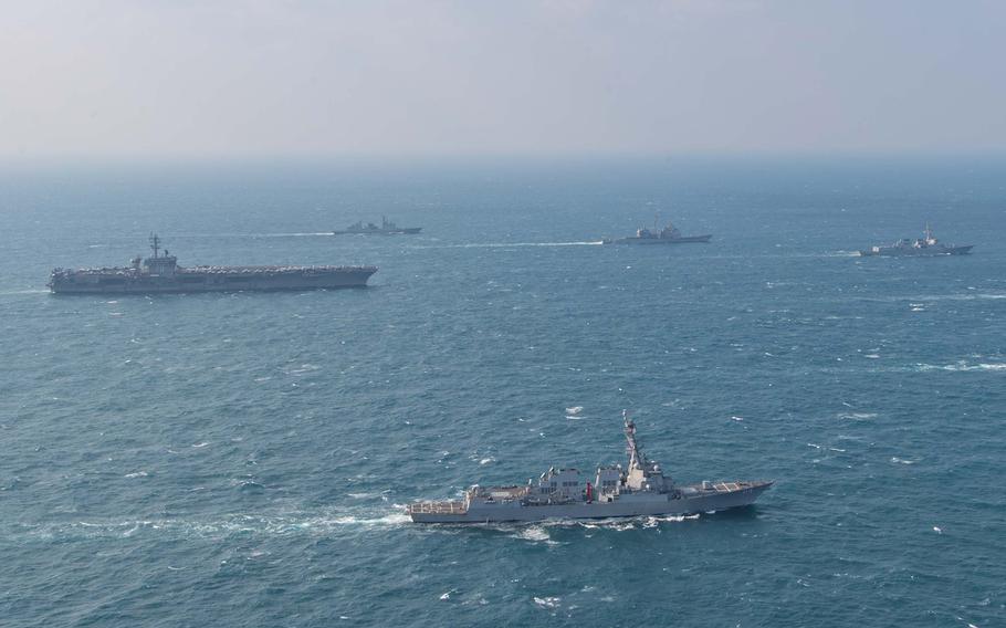 U.S. warships and ships from Japan and South Korea sail in formation through open water with the horizon in the background.