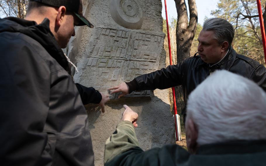 Pawel Urbaniak points to a part of the memorial plaque.