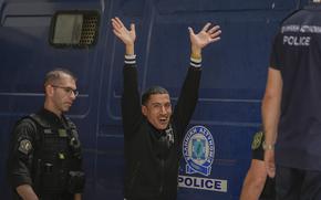 One of nine Egyptians, who was on trial for migrant smuggling, waves to the media persons as he leaves the court in Kalamata, southwestern Greece, on Tuesday, May 21, 2024. A Greek judge dismissed charges against nine Egyptian men accused of causing a shipwreck that killed hundreds of migrants last year and sent shockwaves through the European Union's border protection and asylum operations, after a prosecutor told the court Greece lacked jurisdiction. (AP Photo/Thanassis Stavrakis)