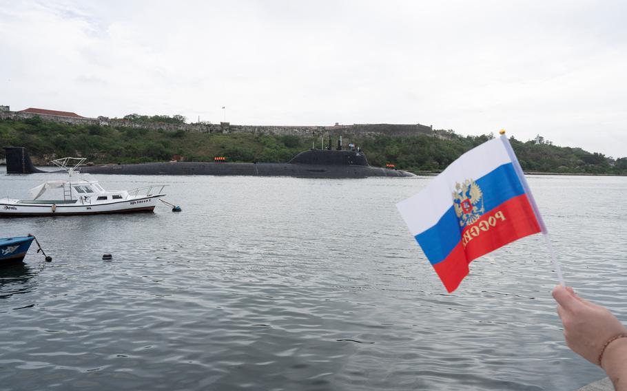 A member of the Russian community holds a flag as Russian nuclear-powered cruise missile submarine Kazan enters the bay in Havana, Cuba, June 12, 2024. 