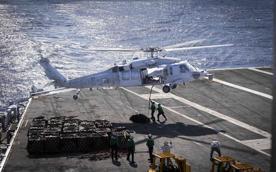 A helicopter hovers over a ship.