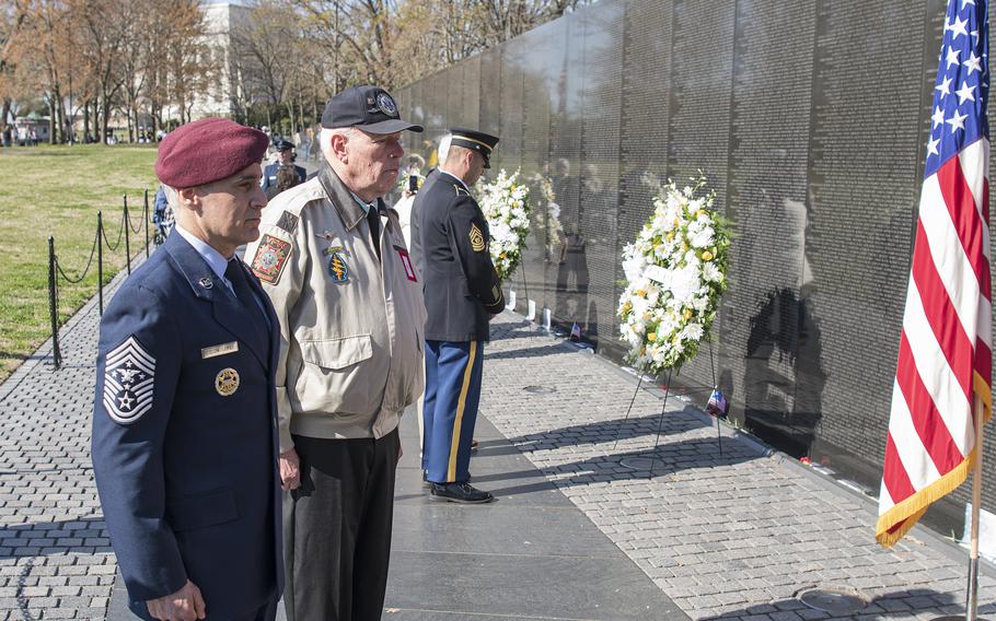 Retired Army Lt. Col. Hank Cramer and Senior Enlisted Advisor to the Chairman of the Joint Chiefs of Staff Ramon Colon-Lozez stand at attention before a wreath placed at the midway point of the Vietnam Veterans Memorial wall on Wednesday, March 29, 2023, in Washington, D.C., where a silent wreath laying ceremony was held in honor of National Vietnam War Veterans Day.