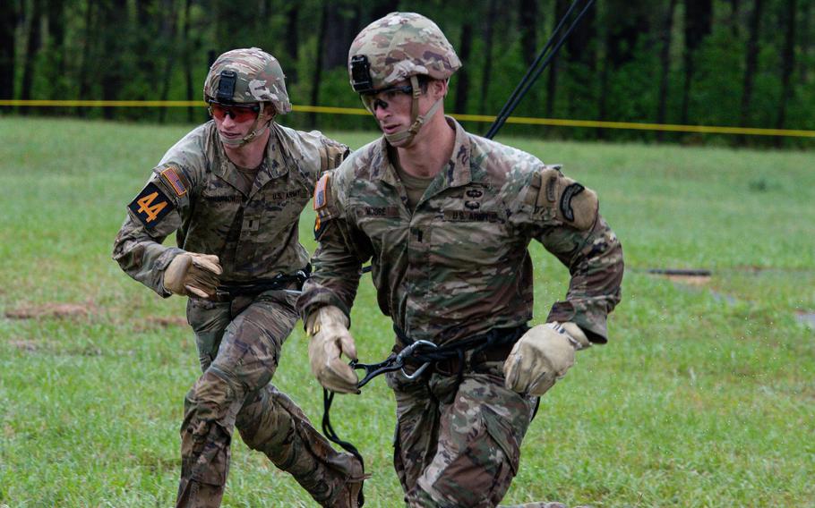 Two soldiers run beside each other in the grass