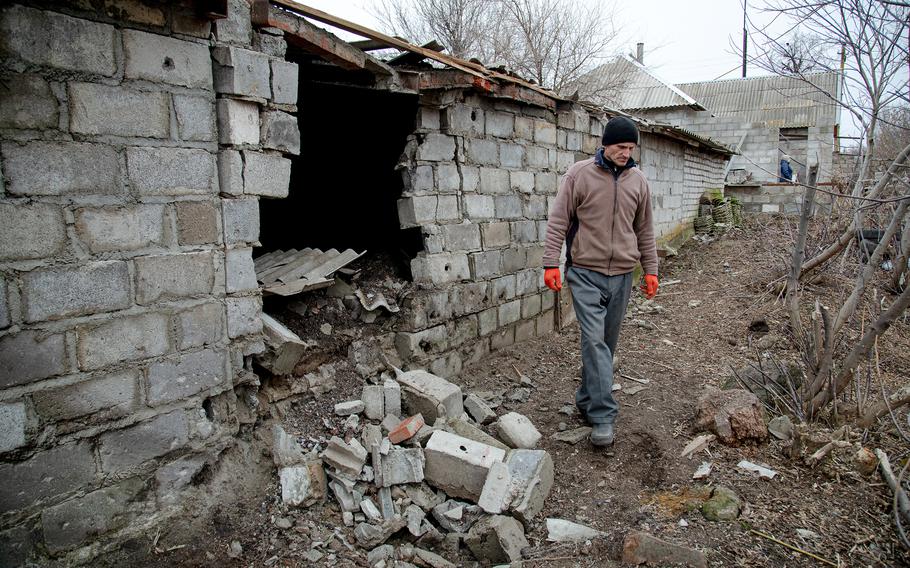 Pavlo Maslinkov walks near a war-damaged farm shed in Hranitne.