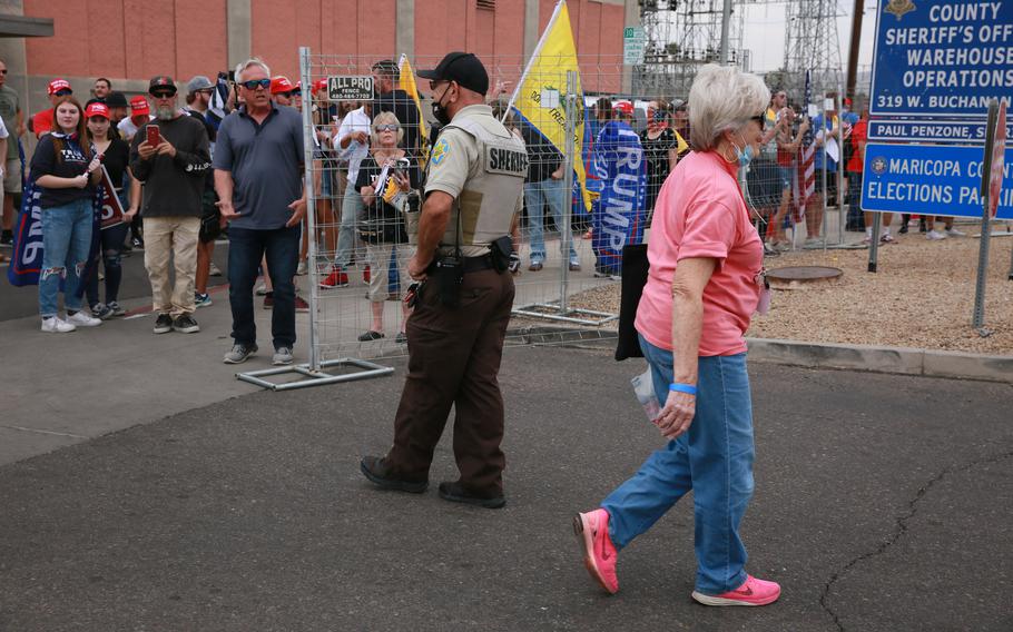 An election worker walks past pro-Trump protesters alleging voter fraud at the Maricopa County Tabulation and Election Center in Phoenix on Nov. 6, 2020. 