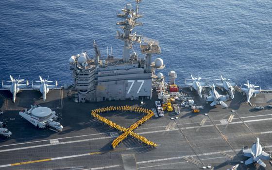 Sailors form a human ribbon on the flight deck of the aircraft carrier USS George H.W. Bush, July 22, 2017, in support of Suicide Prevention and Awareness Month. The Navy has no way of knowing whether commanders are following the requirement to create a suicide crisis prevention plan or whether existing plans are adequate, the Defense Department Inspector General found.