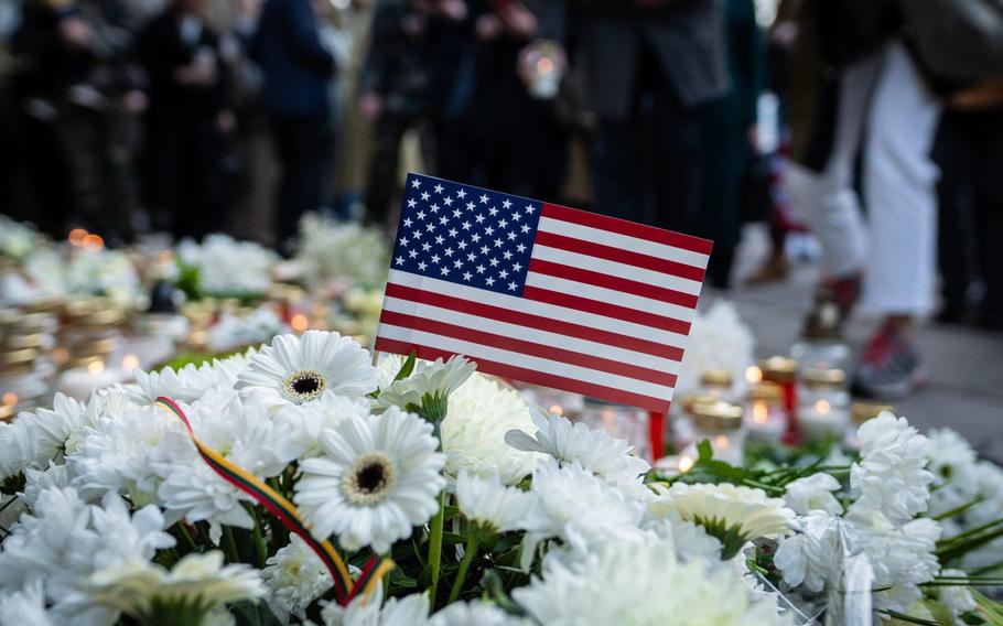 An American flag stands amid a bouquet at a memorial.