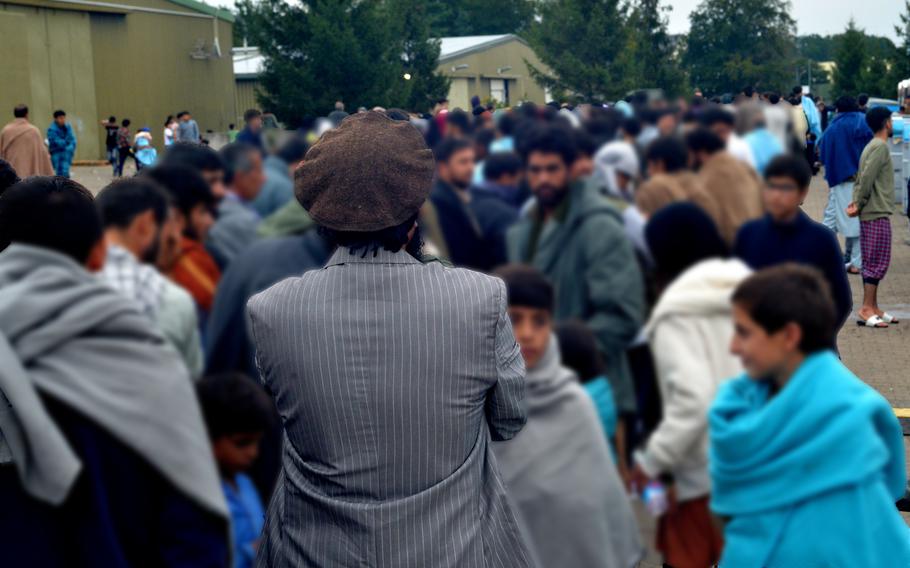 A man wearing the traditional pakol hat of northern Afghanistan waits with hundreds of other evacuees for dinner at Rhine Ordnance Barracks in Kaiserslautern, Germany, Aug. 30, 2021. The Army installation is providing food and shelter for thousands of Afghans who are transiting through Germany, most of whom will eventually be resettled in the U.S. 