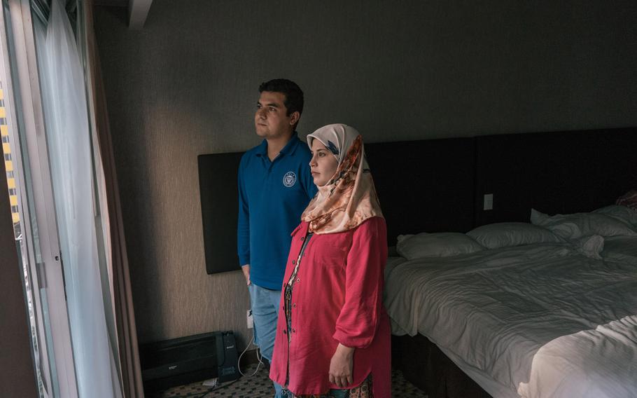Nilofar Quraishi, 26 and seven months pregnant, stands with her husband. Zabihullah Quraishi, 27, in the Mexico City hotel room where they have been living with support from a nongovernmental organization. 
