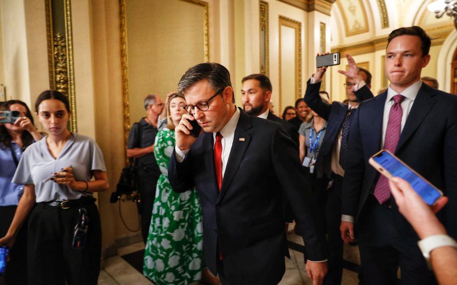 House Speaker Mike Johnson walks as he speaks on the phone.