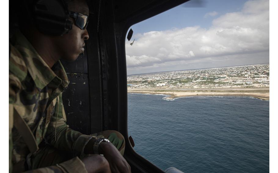 A soldier with the African Union Transition Mission looks at the landscape from a helicopter leaving Mogadishu for Masjid Ali Guduud, Somalia. 