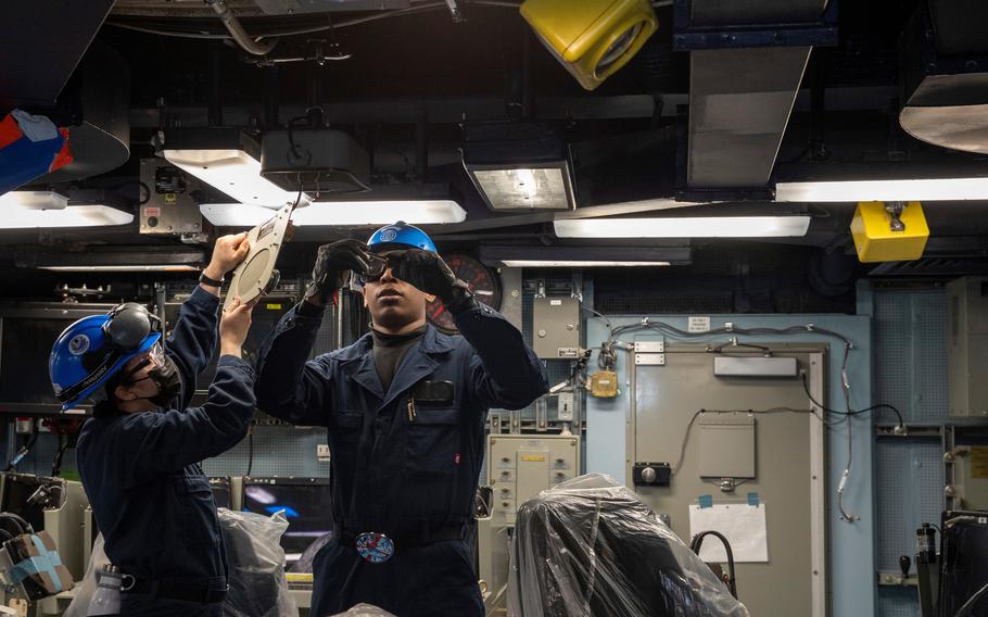 Interior Communications Electrician 3rd Class Aliana Alvarado and Interior Communications Electrician Seaman Dionche Reynolds assigned to combat systems department aboard the aircraft carrier USS George Washington examine the interior components of a shipboard public announcing system speaker on March 21, 2022.