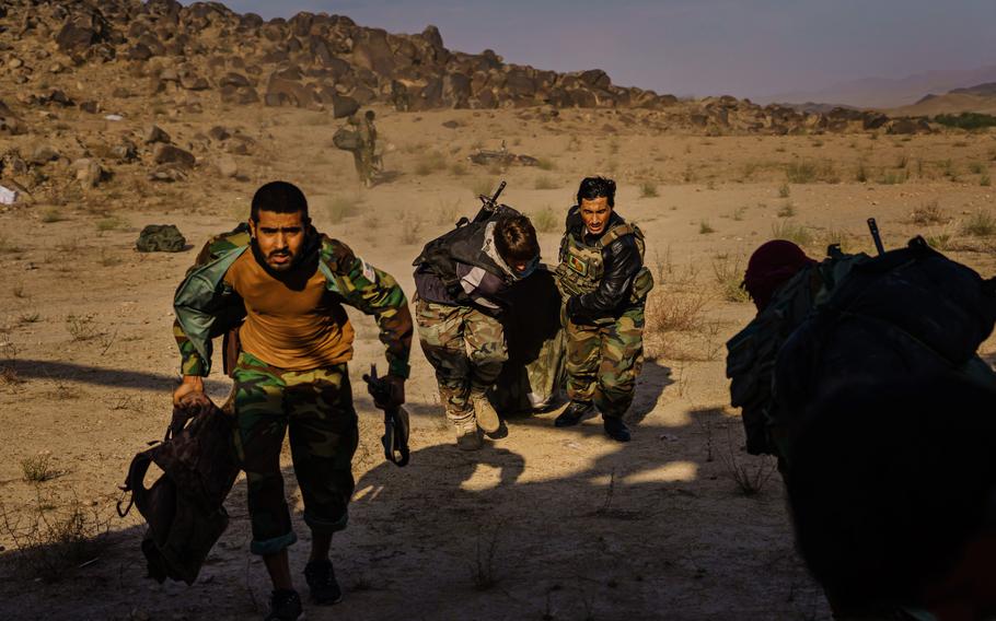 Soldiers dragging a sleeping bag with their belongings run toward a waiting UH-60 Blackhawk under fire from the Taliban in the Shah Wali Kot district of Kandahar, Afghanistan. 