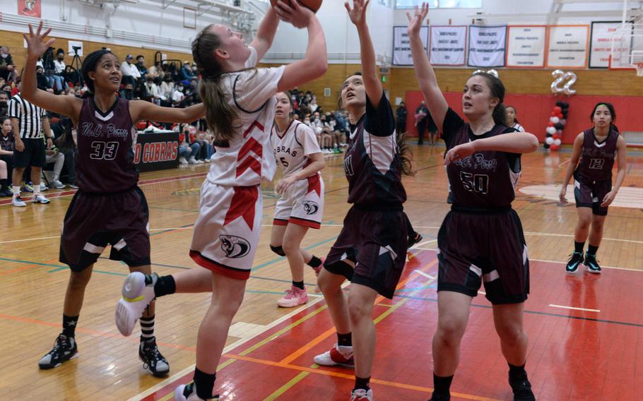 E.J. King's Madylyn O'Neill puts up a shot against Matthew C. Perry defenders Breaunna Hayes, Sophia Nye and Jacqueline Wentling during Friday's DODEA-Japan girls basketball game. The Cobras won 58-10.