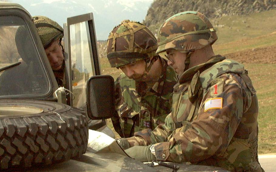 Capt. Keith Igyato, commander of B Troop, Task Force Saber in Macedonia, confers over a map with two British electronic warfare specialists, March 29, 1999, near the Yugoslav border. Soldiers from the 1st Infantry Division were patrolling along the troubled Yugoslav border to help make sure Slobodan Milosevic’s forces didn’t try to make an end run into neighboring Macedonia while NATO warplanes pressed their attack.