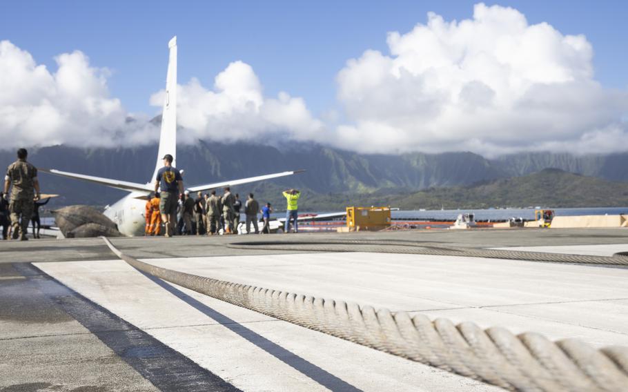 Private industry diving and salvage experts working alongside U.S. Navy sailors and Marines use a hydraulic cable puller to tow a U.S. Navy P-8A Poseidon, with the assistance of inflatable salvage roller bags, from waters just off the runway at Marine Corps Air Station Kaneohe Bay, Marine Corps Base Hawaii, Dec. 2, 2023. 