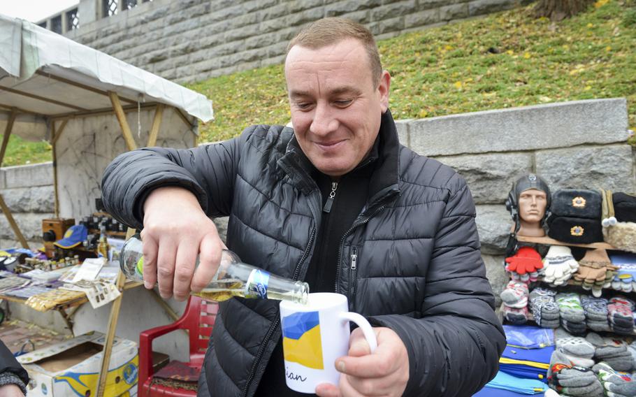 Oleg Boika pours a bottle of beer into a mug as an air raid siren blares in Kyiv, Ukraine, on Oct. 27, 2022. The street vendor says he cannot abandon his cart to get to a shelter during alerts, so he and other hawkers said they can only look up at the sky and hope for the best.