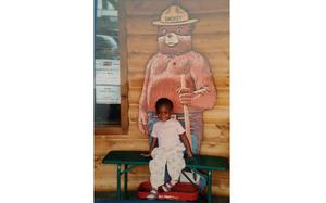 Deidra Goodwin poses with an image of Smokey Bear as a child.