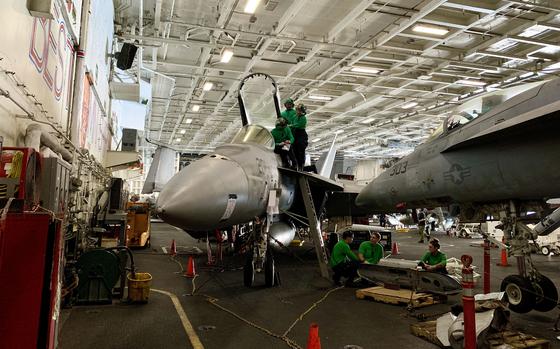 Sailors work on an F/A-18 Super Hornet in the hangar bay of the aircraft carrier USS Dwight D. Eisenhower on March 20, 2024. About 5,000 sailors are assigned to the deployed ship.
