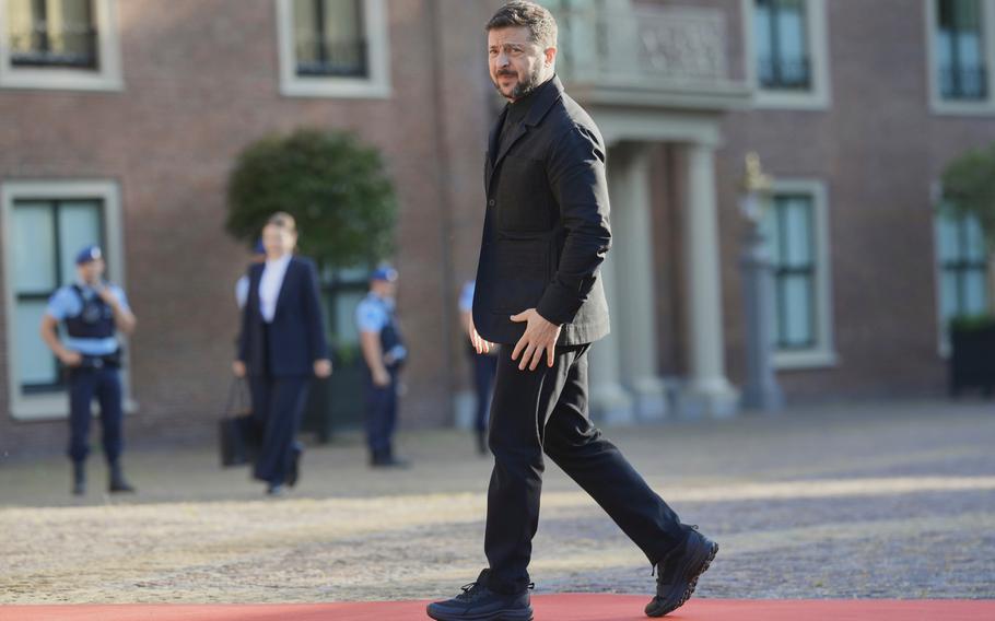 Volodymyr Zelenskyy in a suit, walking with his hands at his sides.