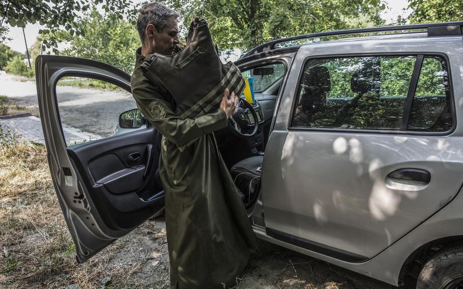 Father Vitalii Kester packs a flak jacket into his car on the way to the front-line Mass. 