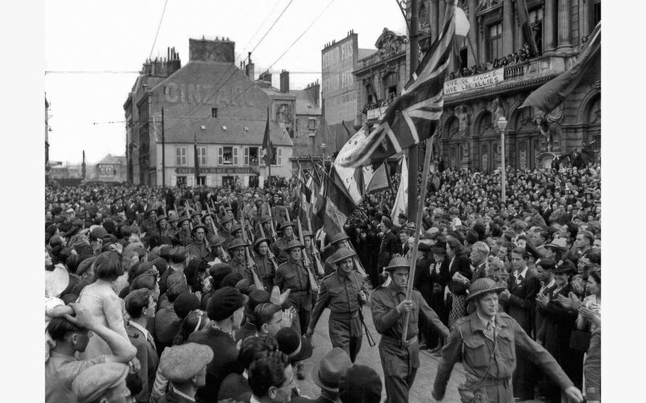 Symbolic of the united spirit with which the Allies are forging the liberation of France from the Nazis, American and British flags march with the Tricolor of France in Cherbourg on the annual observance of Bastille Day, July 14, 1944. These British Tommies drew vociferous applause from the citizens of the Normandy port as they paraded the streets of the city. 
