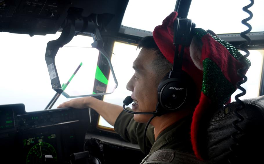 Air Force Capt. Timothy Kim grins from the pilot's seat of a C-130J Super Hercules after a successful Operation Christmas Drop mission in the Federated States of Micronesia, Wednesday, Dec. 7, 2022. 