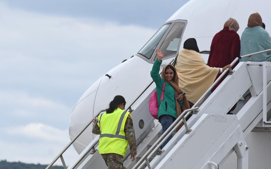 A woman waves before boarding a commercial flight taking evacuees from Afghanistan to the United States. The Boeing 767 departed Ramstein Air Base, Germany, on Aug. 26, 2021, for Dulles International Airport near Washington, D.C.