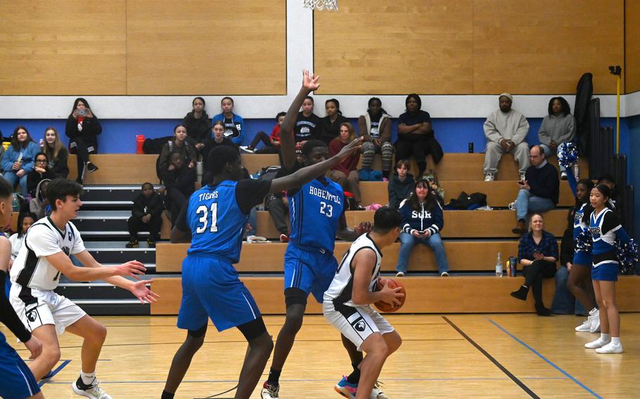 AFNORTH’s Anthony Romar drives to the basket while being met by Hohenfels defenders Joel Idowu, left, and Jacob Idowu during a game against the Tigers at Hohenfels High School on Jan. 13, 2024.